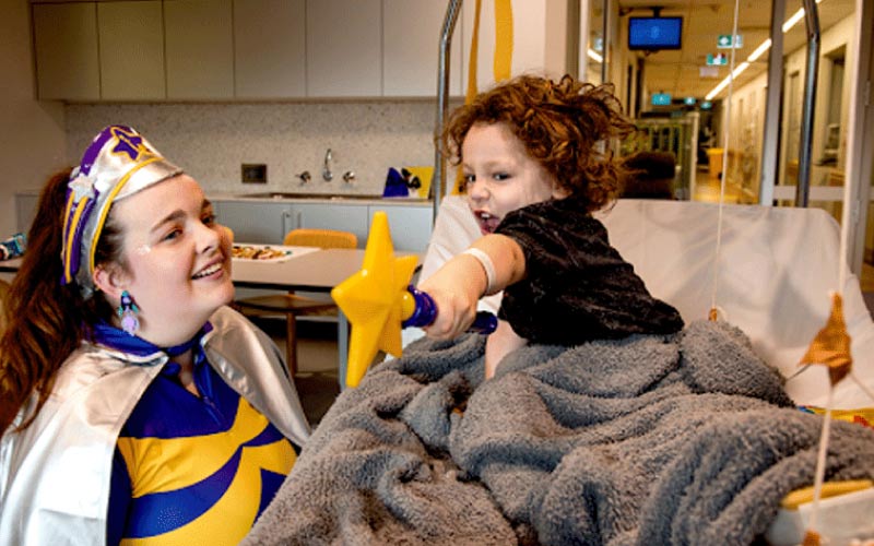 Jaxon, a smiling four-year-old, recovering in a hospital bed after a broken femur.